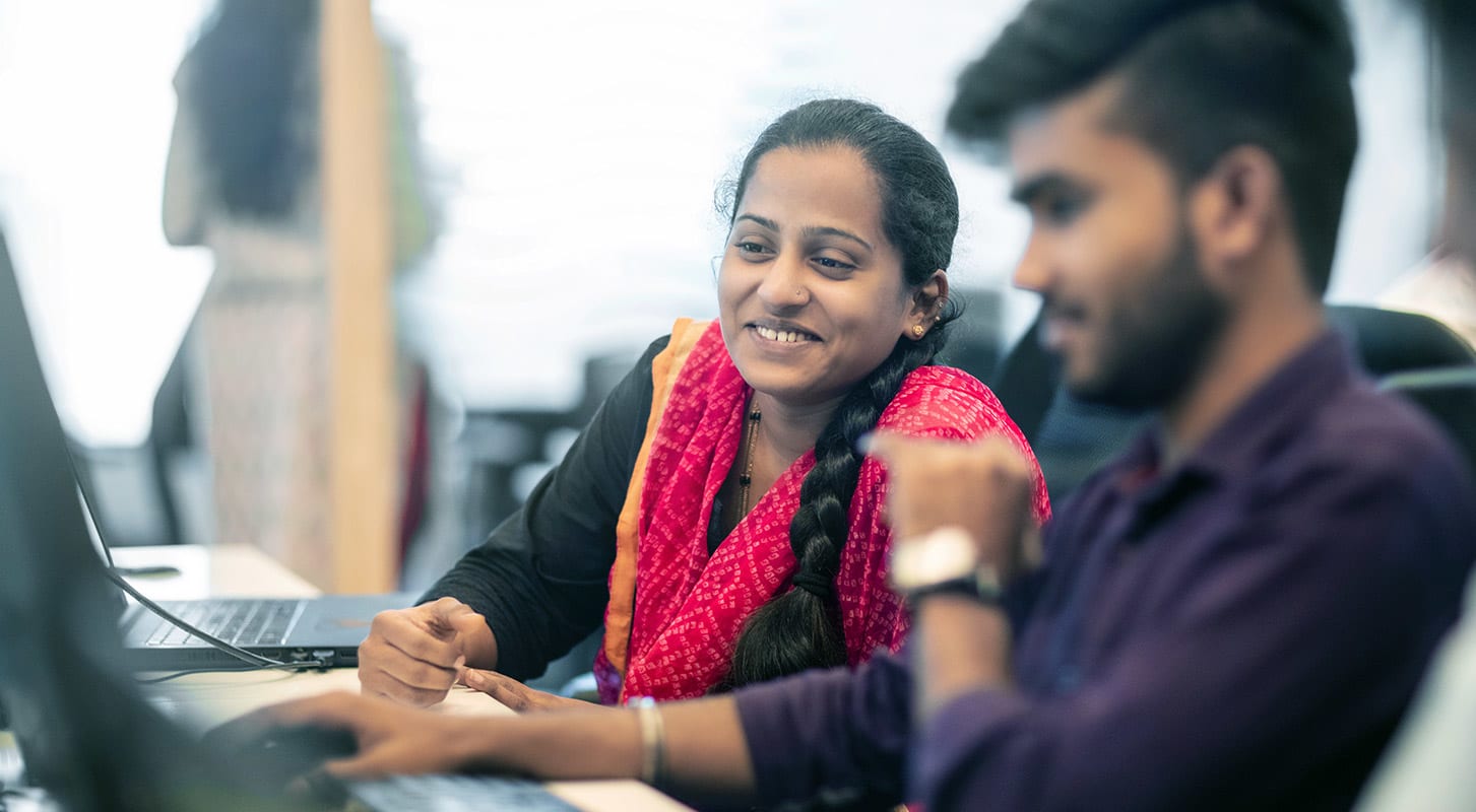A woman and a man collaborating on a computer, focused on their work.
